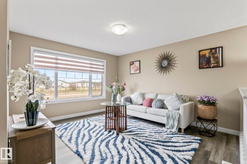 Spacious living area featuring large windows with horizontal blinds, light wood-finish flooring, and neutral wall tones - 8431 216 St Nw, Edmonton, AB - Indoor Photo Showing Other Room