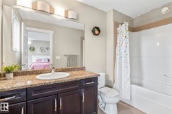 Bathroom featuring a dark wood-finish vanity with a light brown speckled countertop, an undermount sink with a chrome faucet, and a large wall-mounted mirror - 