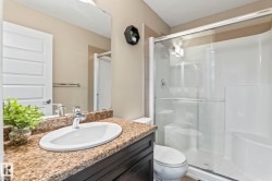 Bathroom featuring a vanity with an oval undermount sink, a granite-look countertop, dark wood-finish cabinetry, a chrome faucet, and a large wall-mounted mirror - 