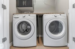 Laundry area featuring a front-load washer and dryer, dark wood-finish cabinetry, and a stone-look countertop - 
