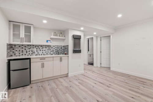 Wet bar featuring white cabinetry, hexagonal tile backsplash, and a compact refrigerator - 8431 216 St Nw, Edmonton, AB - Indoor