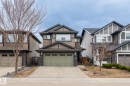 Multi-level home featuring a light green double garage door, stone veneer accents, and dark trim details - 8431 216 St Nw, Edmonton, AB  - Outdoor With Facade 
