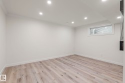 Spacious room featuring wood-finish flooring, recessed ceiling lighting, a window with horizontal blinds, and white baseboards - 