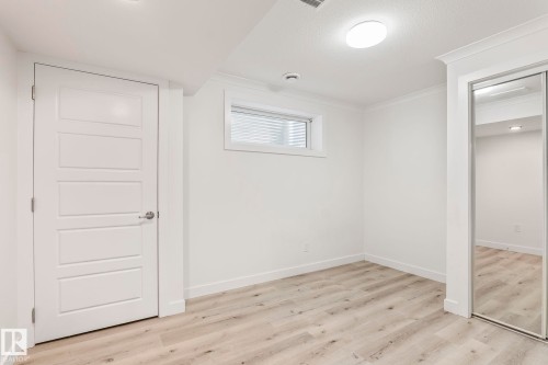 Spacious room featuring wood-finish flooring, white walls, and crown molding - 8431 216 St Nw, Edmonton, AB - Indoor Photo Showing Other Room