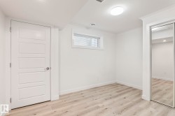 Spacious room featuring wood-finish flooring, white walls, and crown molding - 