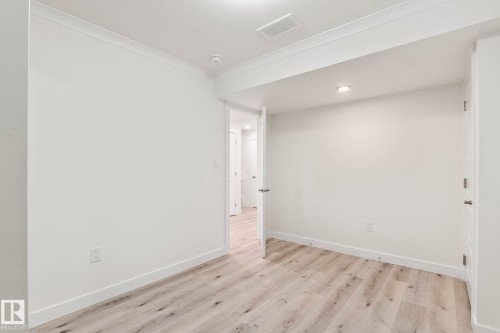 Light wood-finish flooring complements white walls with crown molding and baseboards - 8431 216 St Nw, Edmonton, AB - Indoor Photo Showing Other Room