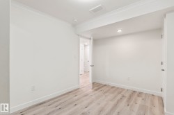 Light wood-finish flooring complements white walls with crown molding and baseboards - 