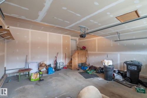 Unfinished garage space featuring a concrete floor, exposed drywall, and an automatic garage door opener - 8431 216 St Nw, Edmonton, AB - Indoor Photo Showing Garage