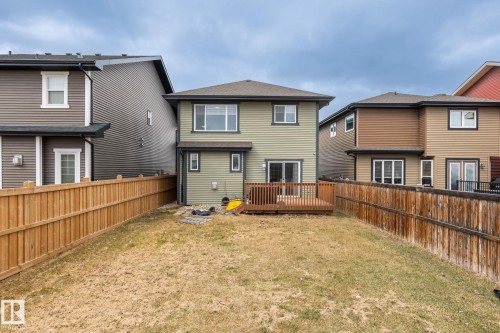 Expansive backyard featuring a wooden deck, sliding patio door access, and full perimeter fencing - 8431 216 St Nw, Edmonton, AB - Outdoor With Exterior