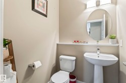 Pedestal sink with chrome faucet, oval mirror, and wall-mounted light fixture - 