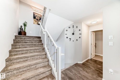 The property features an interior staircase with carpeted treads and a white banister with metal spindles, complemented by light gray walls - 2329 82 Street, Edmonton, AB - Indoor Photo Showing Other Room