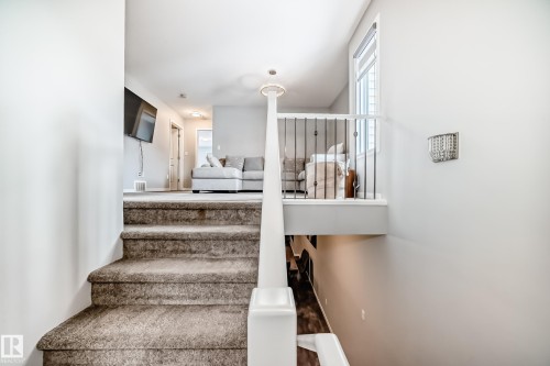 Staircase with carpeted steps leading to an upper landing area featuring a white railing with black spindles and a window with blinds - 2329 82 Street, Edmonton, AB - Indoor Photo Showing Other Room