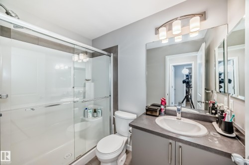 Bathroom featuring a glass-enclosed shower, a toilet, a vanity with a white sink, and a large mirror - 2329 82 Street, Edmonton, AB - Indoor Photo Showing Bathroom