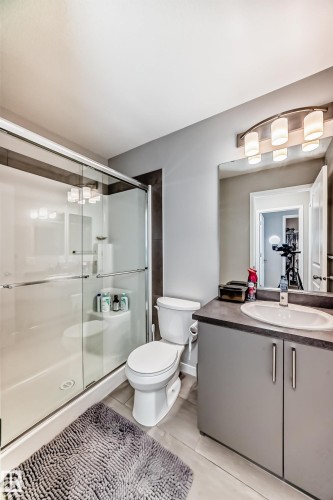 Bathroom featuring a glass-enclosed shower, a toilet, and a vanity with a sink and cabinets - 2329 82 Street, Edmonton, AB - Indoor Photo Showing Bathroom