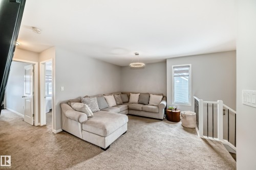 Inviting living space featuring light grey walls, carpeted flooring, and a modern chandelier - 2329 82 Street, Edmonton, AB - Indoor Photo Showing Living Room