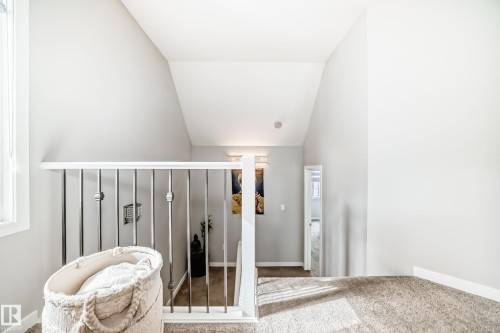 The property features an interior stairway with a white handrail and vertical metal balusters, and a carpeted landing - 2329 82 Street, Edmonton, AB - Indoor Photo Showing Other Room