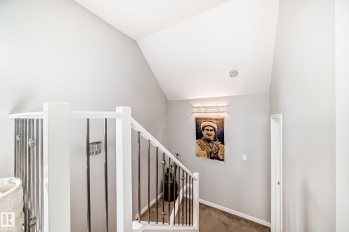 The property features a staircase with white balusters and dark metal spindles, and light-colored walls - 2329 82 Street, Edmonton, AB - Indoor Photo Showing Other Room
