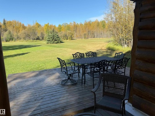 Spacious wooden deck overlooking a substantial grassy area, framed by mature trees - 63218 Range Road 254, Rural Westlock County, AB 
