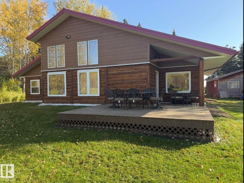 Wood-sided exterior featuring large windows with white trim, a covered deck, and a red-toned roof - 63218 Range Road 254, Rural Westlock County, AB 