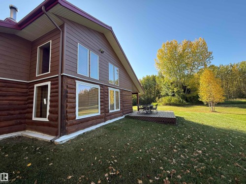 Brown log-style siding exterior with white window trim and a wood-finish deck - 63218 Range Road 254, Rural Westlock County, AB 