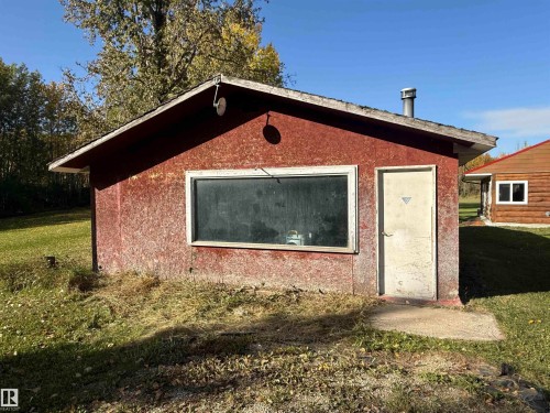 Red-sided structure featuring a single window and an access door, complemented by a gabled roofline and a metal vent - 63218 Range Road 254, Rural Westlock County, AB 