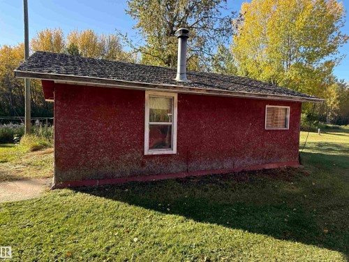 Detached structure featuring red siding, a dark shingle roof, and a visible chimney - 63218 Range Road 254, Rural Westlock County, AB 