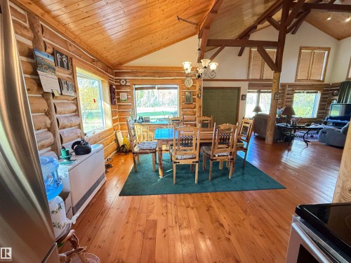 Open concept living area featuring natural log walls, wood-finish flooring, and a vaulted wood-paneled ceiling - 63218 Range Road 254, Rural Westlock County, AB 