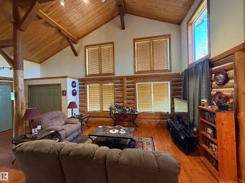 Great room featuring log wall construction, vaulted wood-finish ceiling with exposed beams, wood-finish flooring, and multiple windows - 63218 Range Road 254, Rural Westlock County, AB 