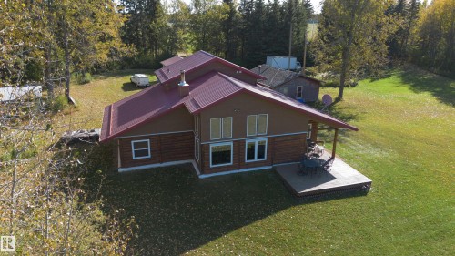 Exterior featuring a red metal roof, wood siding, and white-trimmed windows - 63218 Range Road 254, Rural Westlock County, AB 