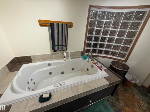 Deep white jetted tub featuring a tiled surround and an adjacent glass block window - 63218 Range Road 254, Rural Westlock County, AB 
