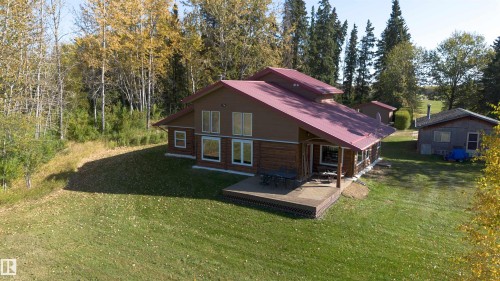 Expansive property featuring a multi-level residence with a red metal roof, a wood and brown siding exterior, and multiple large windows - 63218 Range Road 254, Rural Westlock County, AB 