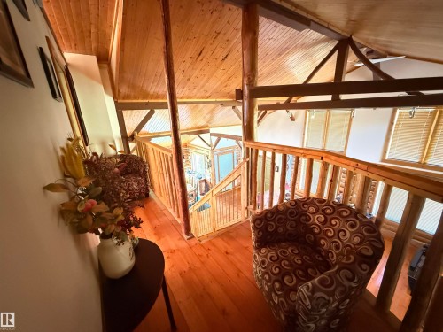 Open loft area featuring wood-finish flooring, natural wood railings, exposed wood beams, and a wood-paneled ceiling - 63218 Range Road 254, Rural Westlock County, AB 