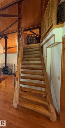 Wood staircase with a natural finish, featuring a matching wood railing and balusters - 63218 Range Road 254, Rural Westlock County, AB 