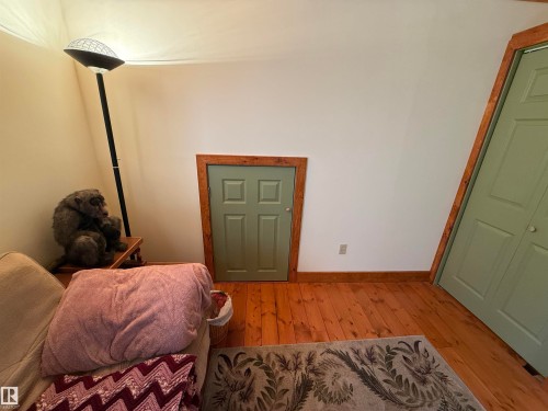 Wood-finish flooring with natural wood trim, white walls, and a light green paneled door - 63218 Range Road 254, Rural Westlock County, AB 