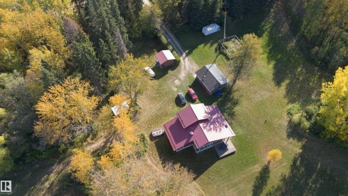 Expansive property featuring a main residence with a red-toned roof, a secondary structure, and a detached shed, surrounded by mature trees with autumnal foliage - 63218 Range Road 254, Rural Westlock County, AB 