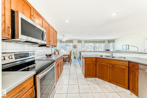 Kitchen featuring wood cabinetry, stainless steel appliances, and light-toned tile flooring - 17 Springfield Crescent, St. Albert, AB - Indoor Photo Showing Kitchen With Double Sink