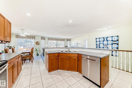 Kitchen featuring wood cabinetry, stainless steel dishwasher, and a double basin sink - 17 Springfield Crescent, St. Albert, AB - Indoor Photo Showing Kitchen With Double Sink
