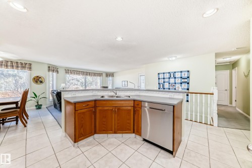 Kitchen island featuring a double-basin sink, stainless steel dishwasher, and wood-finish cabinetry - 17 Springfield Crescent, St. Albert, AB - Indoor Photo Showing Kitchen With Double Sink