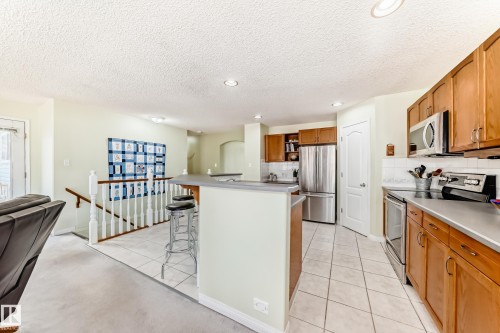 Kitchen featuring wood cabinetry, stainless steel appliances, and a tiled backsplash - 17 Springfield Crescent, St. Albert, AB - Indoor Photo Showing Kitchen