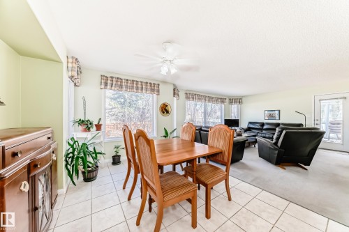 Open-concept living space featuring a dining area with tiled flooring, a wooden dining table, and a ceiling fan - 17 Springfield Crescent, St. Albert, AB - Indoor