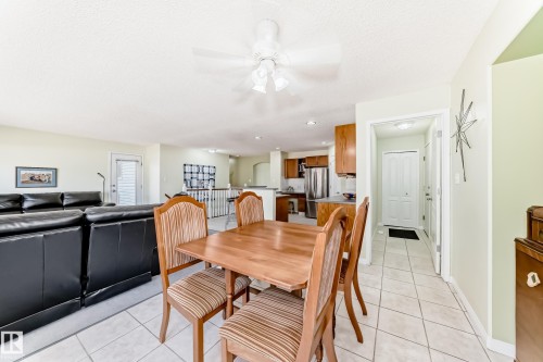 Open-concept living space featuring a dining area with a wood-finish table and four chairs, tile flooring, and a ceiling fan - 17 Springfield Crescent, St. Albert, AB - Indoor Photo Showing Dining Room