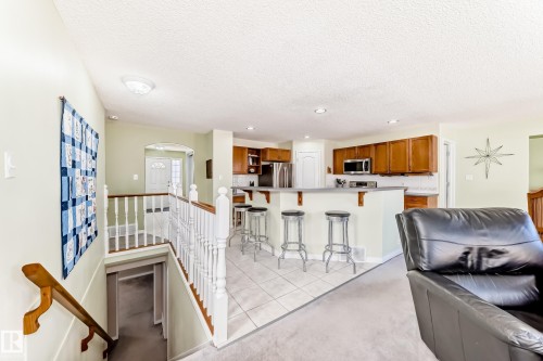 Open-concept kitchen with wood cabinetry, stainless steel appliances, and a breakfast bar - 17 Springfield Crescent, St. Albert, AB - Indoor