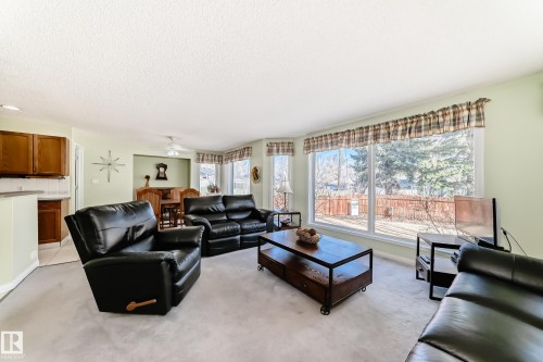 Bright living area featuring expansive windows, light green wall paint, and a textured ceiling - 17 Springfield Crescent, St. Albert, AB - Indoor Photo Showing Living Room