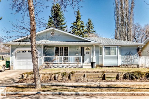 Light blue siding exterior featuring a covered front porch with white railings, an attached single-car garage, and a bay window - 17 Springfield Crescent, St. Albert, AB - Outdoor With Deck Patio Veranda