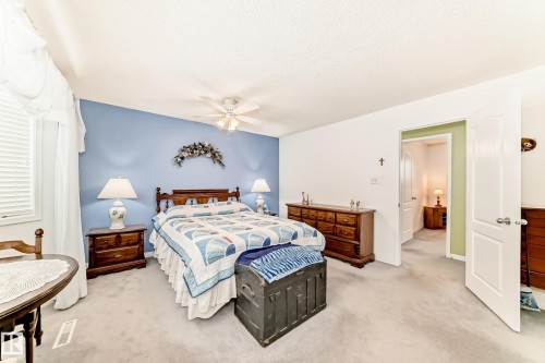 Carpeted bedroom featuring a light blue accent wall and white trim - 17 Springfield Crescent, St. Albert, AB - Indoor Photo Showing Bedroom