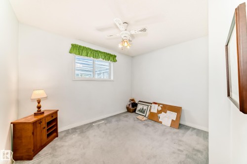 Carpeted room with a ceiling fan light fixture, white walls, and a window with a green valance - 17 Springfield Crescent, St. Albert, AB - Indoor
