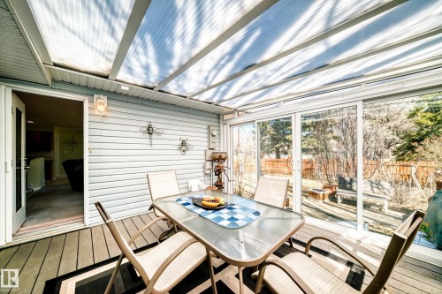 Covered outdoor patio with a translucent slatted roof, sliding glass panel walls, and wood-finish flooring - 17 Springfield Crescent, St. Albert, AB - Outdoor With Deck Patio Veranda