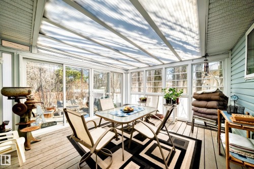 Sunroom featuring a translucent vaulted ceiling, multiple large windows, sliding glass door access to the outdoors, white wood-finish decking, and light blue siding - 17 Springfield Crescent, St. Albert, AB - Indoor