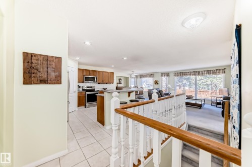 Open-concept kitchen and living area featuring a breakfast bar, stainless steel appliances, wood-finish cabinetry, and recessed lighting - 17 Springfield Crescent, St. Albert, AB - Indoor