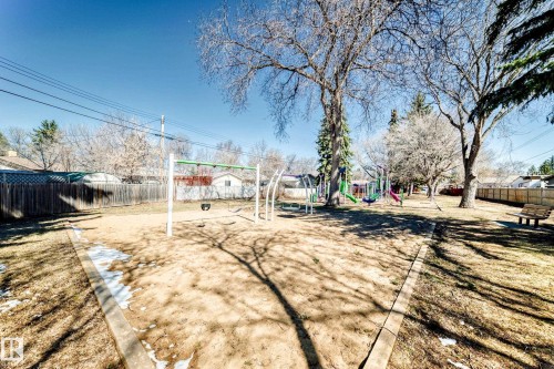 Community playground featuring multiple swing sets, colorful slides, and a climbing structure - 17 Springfield Crescent, St. Albert, AB - Outdoor